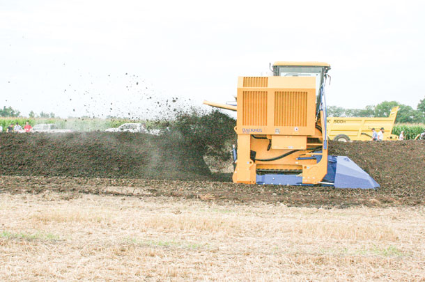 a compost turner churns through a row of compost